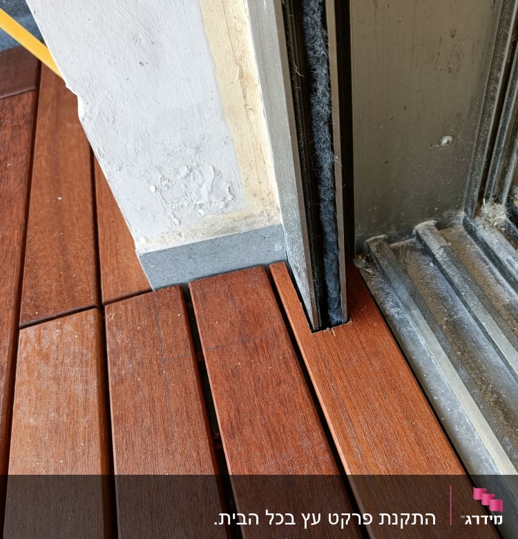רצפת פרקט עץ חום ליד מסגרת דלת מתכתית